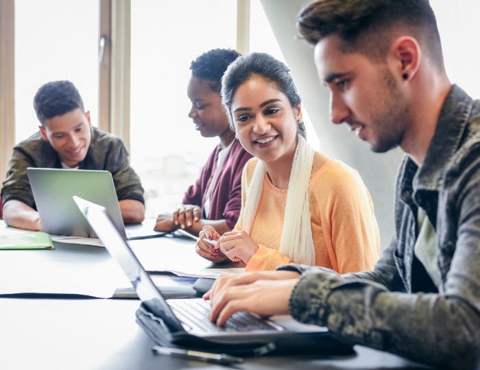 Young man using laptop with woman watching 