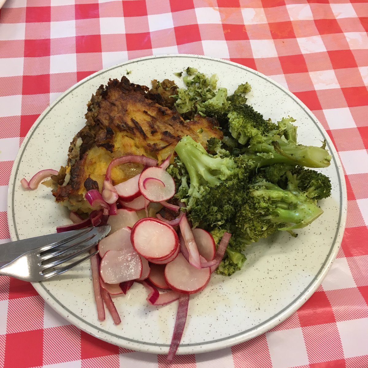 A hearty meal of lentil shepherds pie on a kitsch red and white table cloth